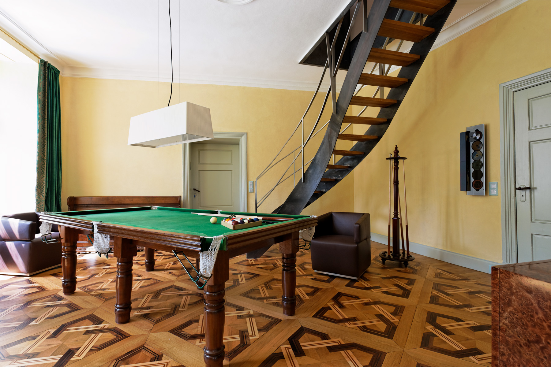 Eine moderne Wendeltreppe aus Roheisen gibt dem Raum eine spannende Dynamik