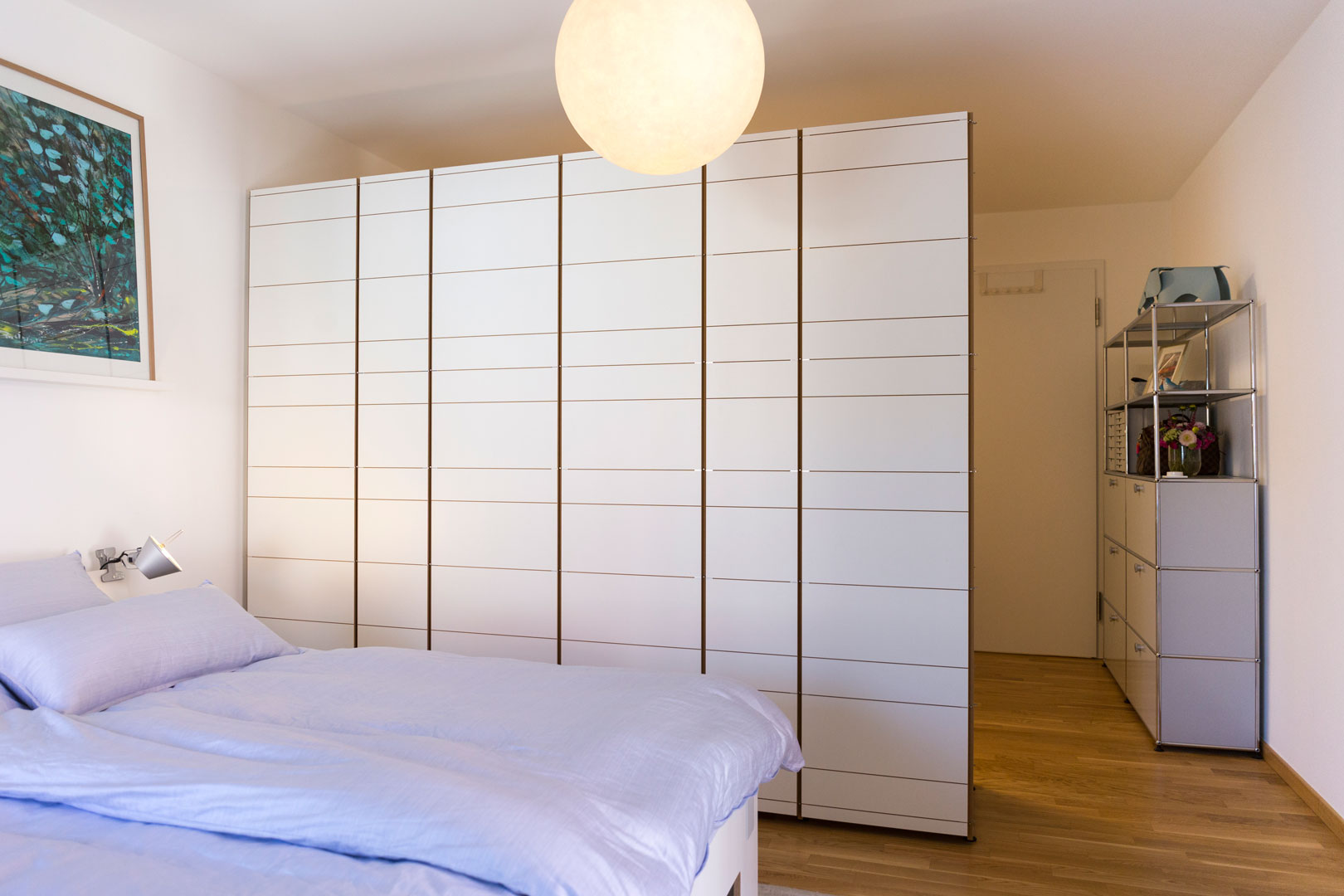 Schlafzimmer mit maßgefertigtem Kleiderschrank als Raumtrennung zum Arbeitsplatz